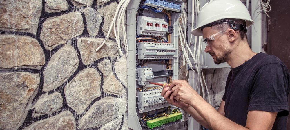 male electrician works in a switchboard with an electrical connecting cab électricité bâtiment